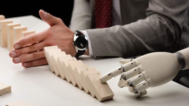 cropped view of robotic hand pushing wooden bricks while man preventing row from falling