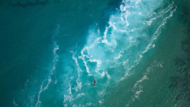 Top view  of a man paddles a kayak in raging sea water