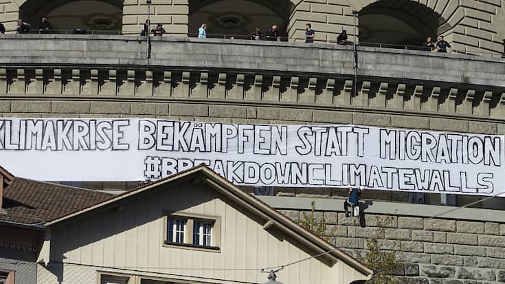 Les activistes de "Break down Climate Walls" ont déroulé une banderole sur la terrasse du Palais fédéral exhortant à "combattre la crise climatique plutôt que les migrants"