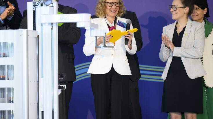 Un robot donne une clé symbolique à Belén Garijo, CEO du groupe Merck (à gauche) et à Séverine Evequoz (à droite), présidente du Grand Conseil vaudois.