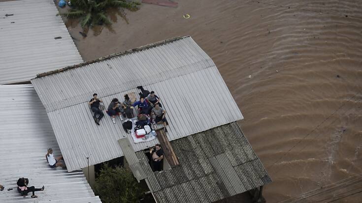 Des personnes attendent sur le toit de leur maison d'être secourues par un hélicoptère de l'armée brésilienne à Porto Alegre au Brésil samedi.