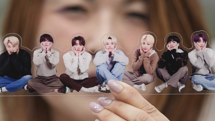 Une fan de groupe de K-pop BTS pose avec une photo de la formation.