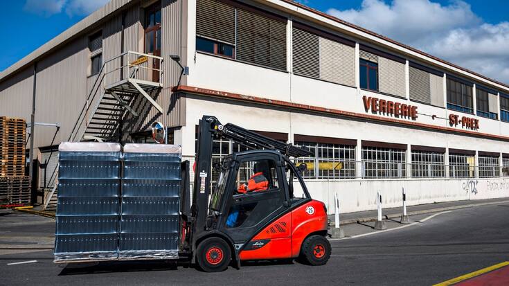 Un ouvrier transporte des bouteilles devant le site du groupe Vetropack