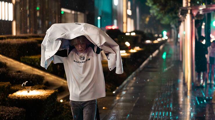 Un homme marche sous les fortes pluies du typhon Bebinca dans une rue à Shangai.