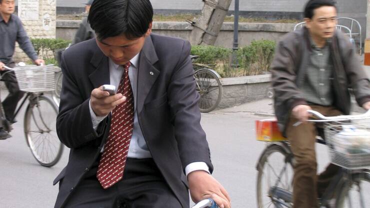 Ce cycliste s'est arrêté pour envoyer un message avec son smartphone. Ce sera la pratique à adopter désormais au Japon où il en coûtera cher de se servir de son engin tout en conduisant un deux-roues (Photo d'illustration).