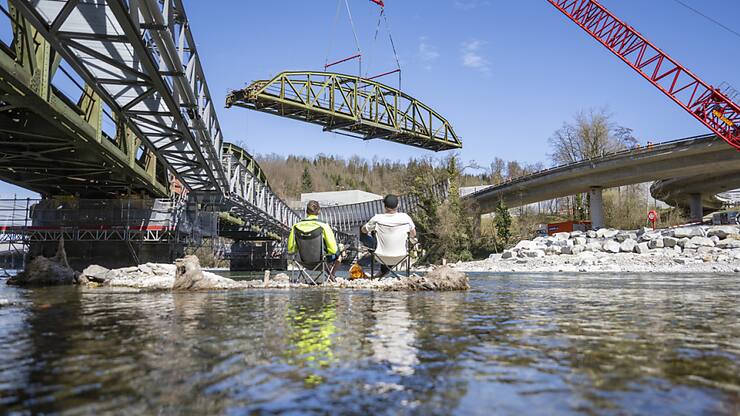 Un des trois éléments du pont de Fluhmühle sur la Reuss est hissé sur la rive par une grue.