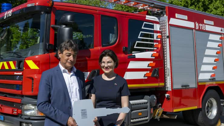 Le directeur de l'ECA Serge Depallens (à gauche) remet symboliquement à Lausanne une clé de camion de pompiers à l'ambassadrice d'Ukraine en Suisse, Irina Venediktova (à droite), devant l'un des dix véhicules de pompiers qui seront remis à l'Ukraine.