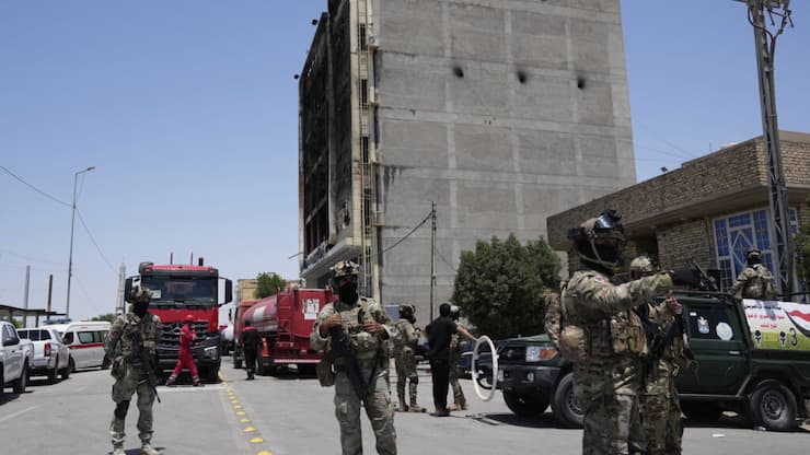 Les forces de sécurité irakiennes rasemblées devant l'immeuble abritant le centre commercial où s'est déclaré l'incendie meurtrier.