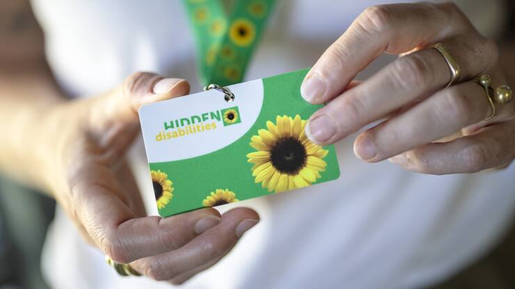 Après les CFF dans certaines gares, l'aéroport de Zurich introduit à son tour la possibilité pour les personnes souffrant d'un handicap non visible de porter un cordon vert à motifs de tournesols autour du cou.