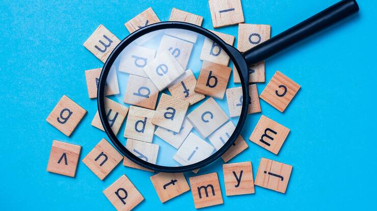 English alphabet made of square wooden tiles with the English alphabet scattered on blue background. The concept of thinking development, grammar.