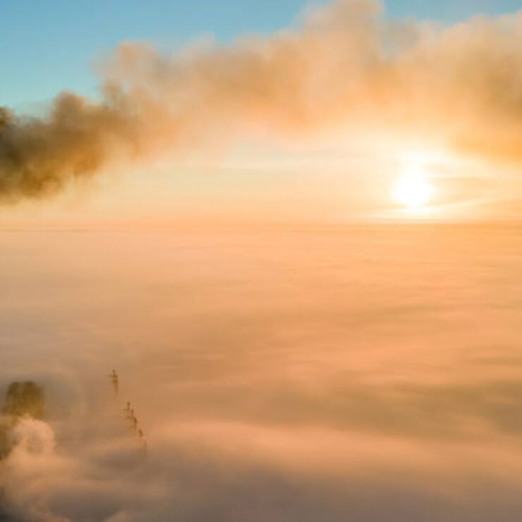 Aerial view of coal power plant high pipes with black smoke moving up polluting atmosphere at sunset.