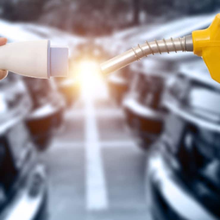 Human hands holding electric plug and gasoline nozzle