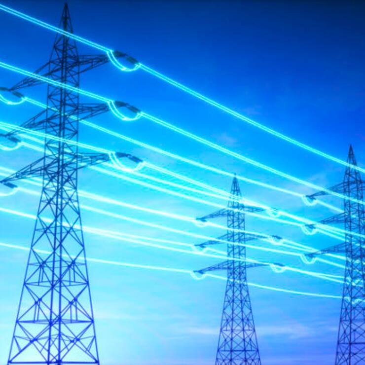 High voltage transmission towers with glowing wires against blue sky - Energy concept