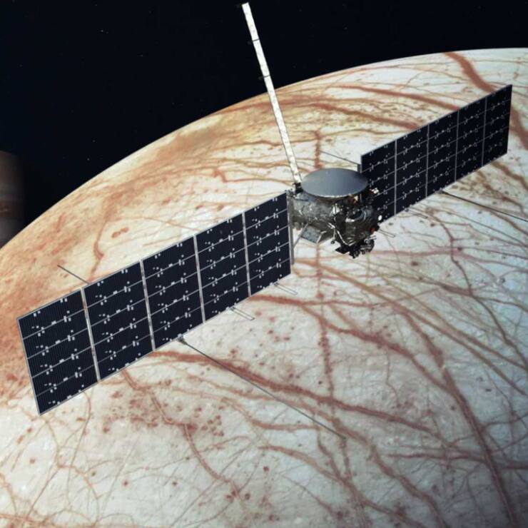 Une image de la NASA avec le vaisseau spatial Europa Clipper au-dessus de la lune, Europa, avec Jupiter à l'arrière-plan à gauche.