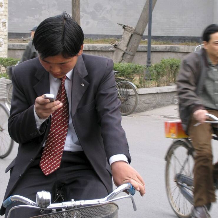 Ce cycliste s'est arrêté pour envoyer un message avec son smartphone. Ce sera la pratique à adopter désormais au Japon où il en coûtera cher de se servir de son engin tout en conduisant un deux-roues (Photo d'illustration).