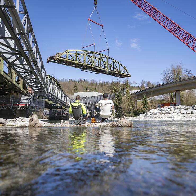 Un des trois éléments du pont de Fluhmühle sur la Reuss est hissé sur la rive par une grue.