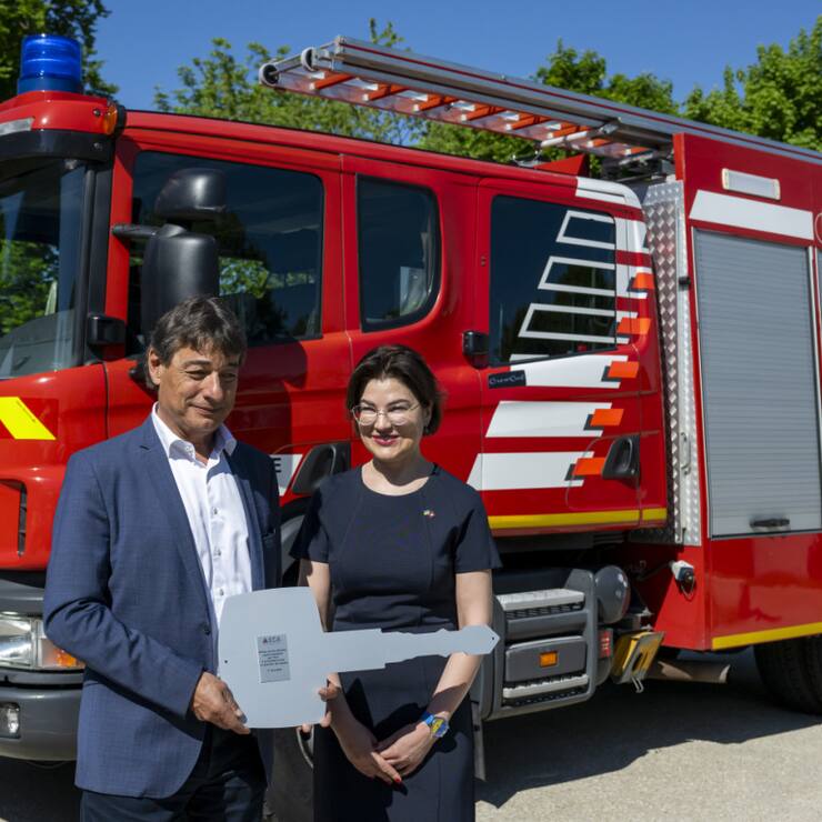 Le directeur de l'ECA Serge Depallens (à gauche) remet symboliquement à Lausanne une clé de camion de pompiers à l'ambassadrice d'Ukraine en Suisse, Irina Venediktova (à droite), devant l'un des dix véhicules de pompiers qui seront remis à l'Ukraine.
