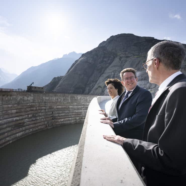 Barbara Egger-Jenzer présidente du conseil d'administration des KWO (gauche), le conseiller fédéral Albert Roesti (centre) et Daniel Fischlin CEO des KWO se tiennent sur le nouveau barrage de Spitallamm, haut de 113 mètres au lac du Grimsel vendredi.