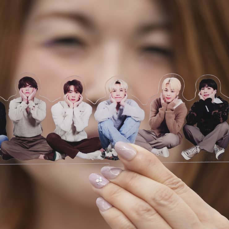 Une fan de groupe de K-pop BTS pose avec une photo de la formation.