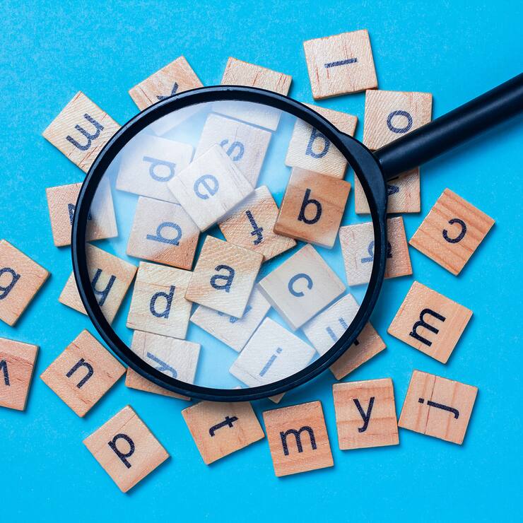 English alphabet made of square wooden tiles with the English alphabet scattered on blue background. The concept of thinking development, grammar.