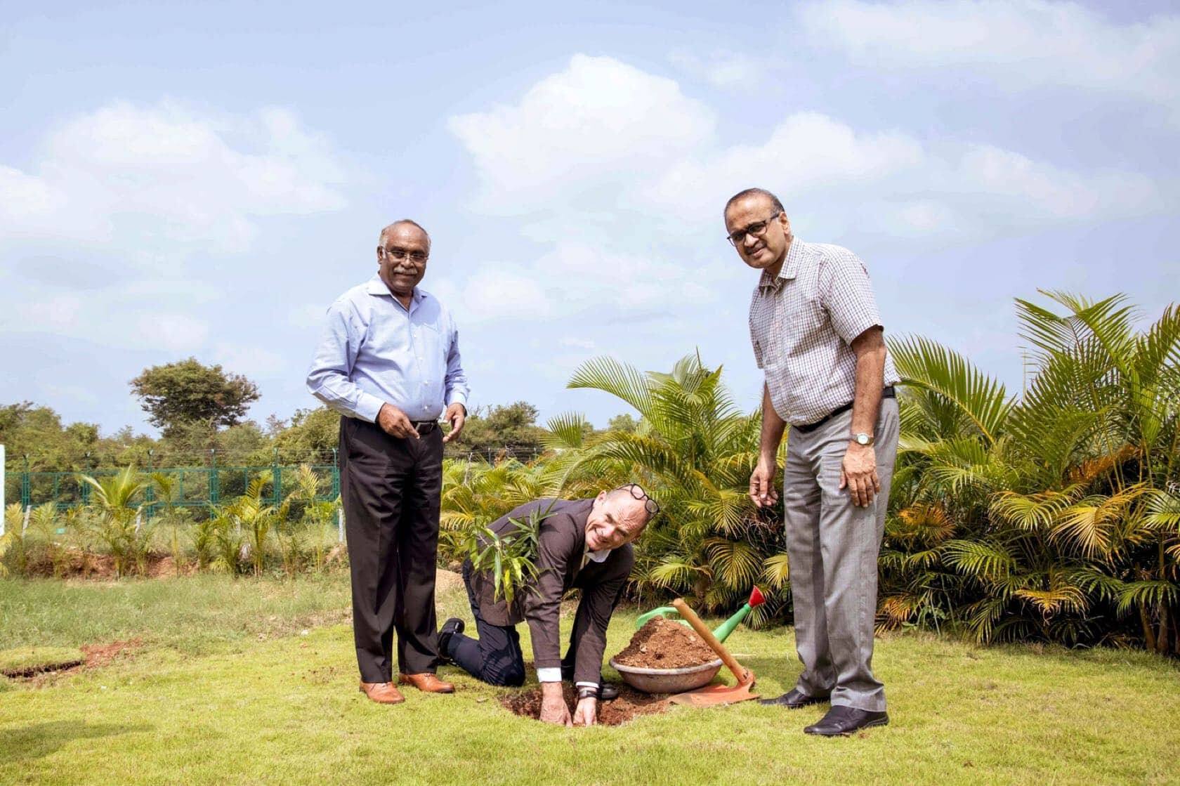 Sam Cherian (à g.) invite le visiteur à planter un manguier dans les jardins de l’usine Cleanfix Schevaran de Mysore.