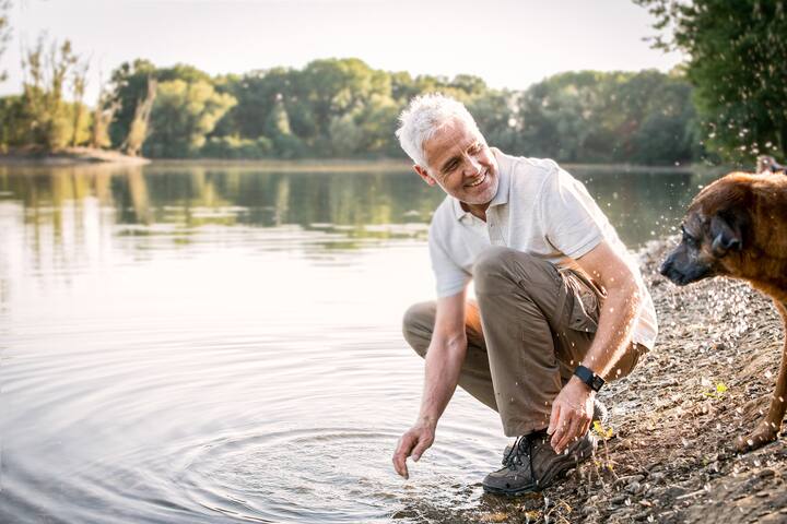 Senior, Mann spielt mit seinem Hund am See, NRW, Deutschland
